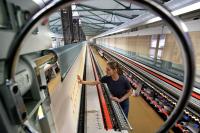 Eine Polster- und Dekorationsnäherin arbeitet an einer fast 30 Meter langen computergesteuerten Stickmaschine zur Fertigung von Gardinen der Marke Plauener Spitze.