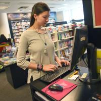 Eine Buchhändlerin prüft im Warensystem den Bestand an Büchern und bestellt fehlende Produkte nach.